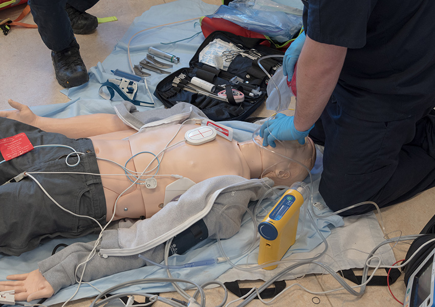 EMS training mannequin equipped with full medical practice gear.